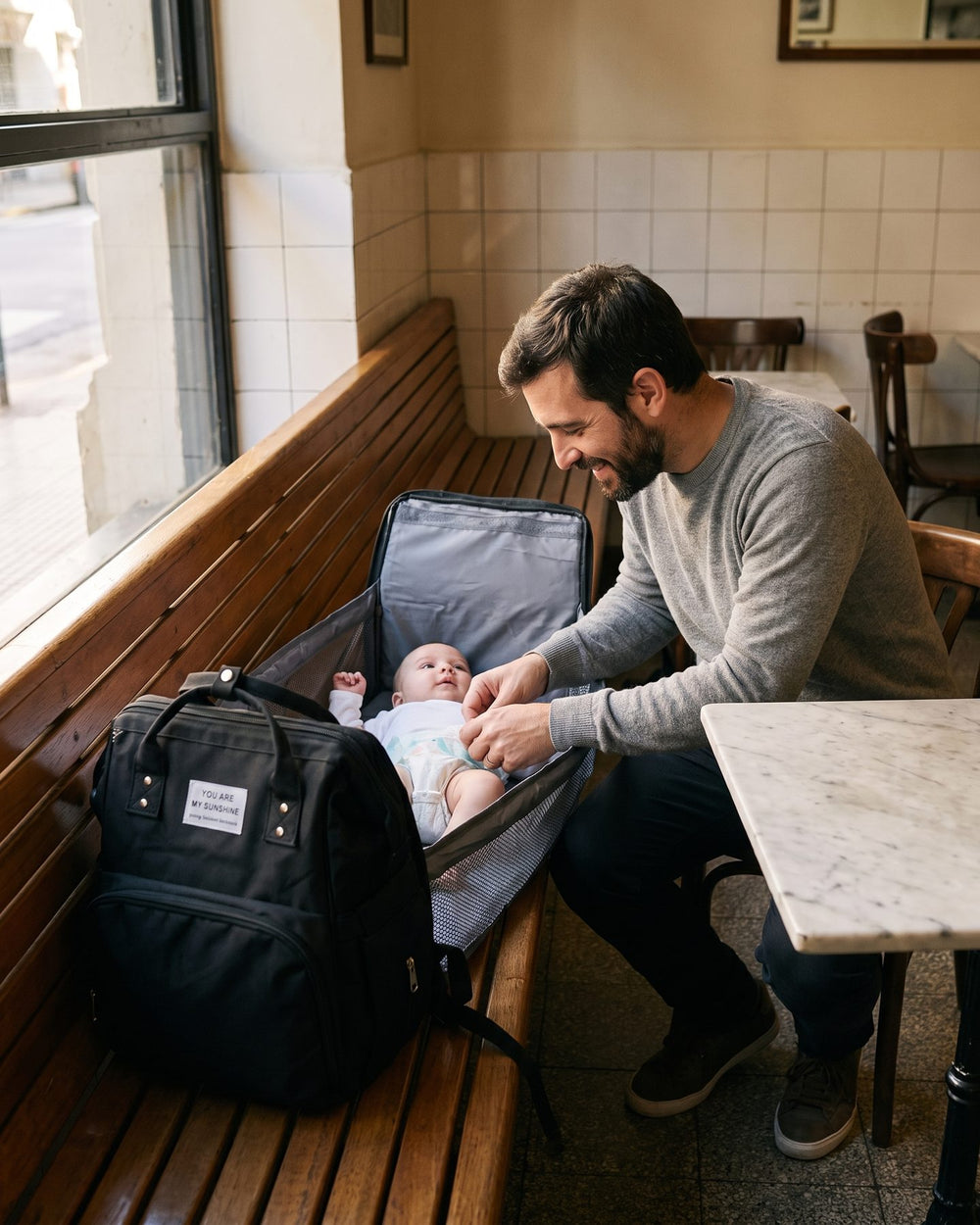 Papá cambiando al bebé sobre el cambiador de la mochila