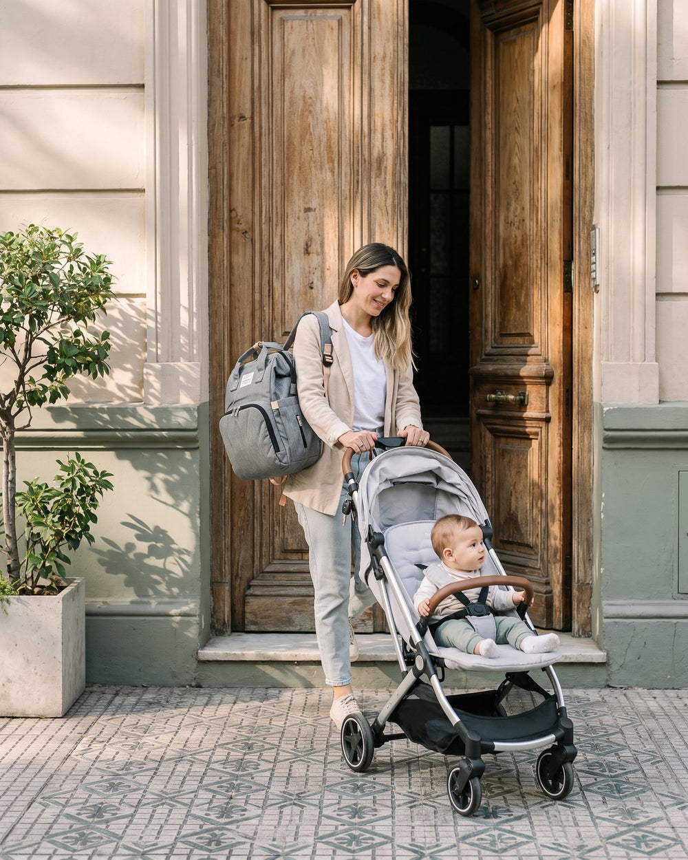 Mamá saliendo de casa con la mochila a la espalda y el cochecito