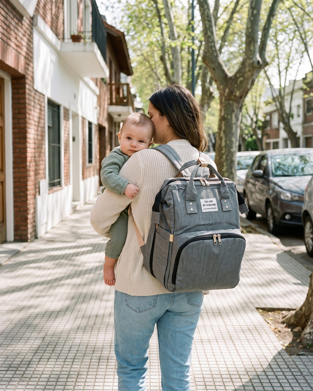 Mamá con la mochila a la espalda y el bebé a upa, con luz natural